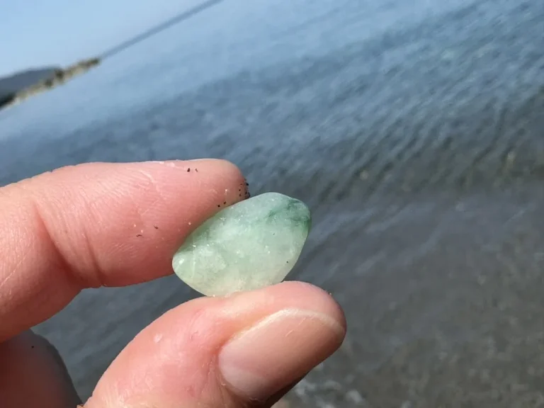 水辺で指先に持った淡緑色で半透明のヒスイ輝石岩と思われる小礫